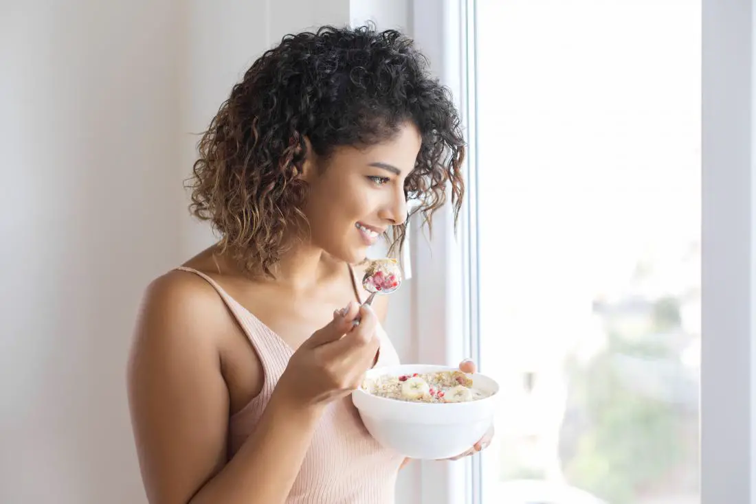 woman-looking-out-the-window-while-eating-oatmeal
